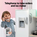 Girl using a telephone in a pretend kitchen play set with an ice maker feature.